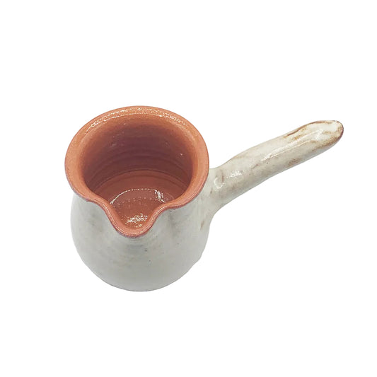 A small handmade ceramic pitcher with a rounded body, a pouring spout, and a long handle, shown on a plain white background.