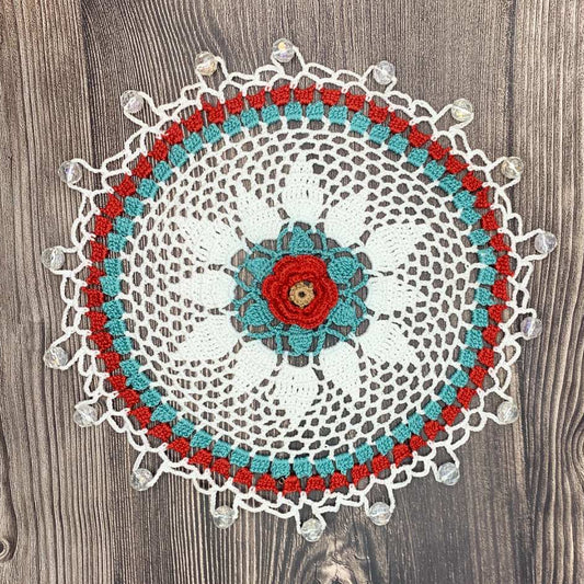 Crocheted doily with a floral center on a wooden surface. Cotton jug cover