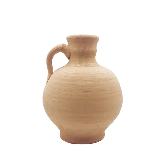 A handmade terracotta clay jug with a rounded body, short neck, and side handle, photographed on a seamless white studio background.