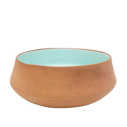 Ceramic bowl with terracotta exterior and light blue interior on a white background