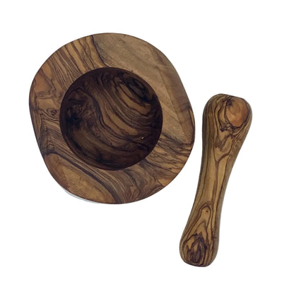 A handcrafted olive wood mortar and pestle set, photographed from an overhead angle on a white surface.